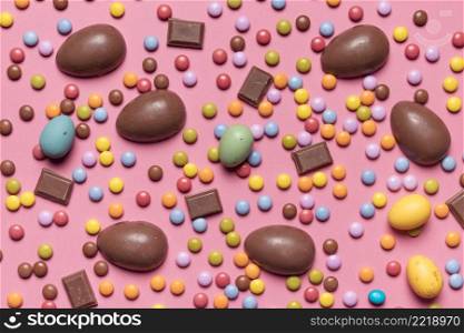 elevated view gem candies chocolate easter eggs pink background
