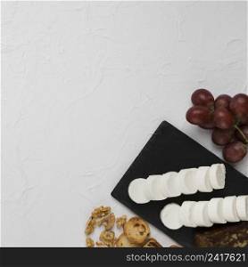 elevated view goat cheese slice slate rock with grapes bread walnut textured backdrop