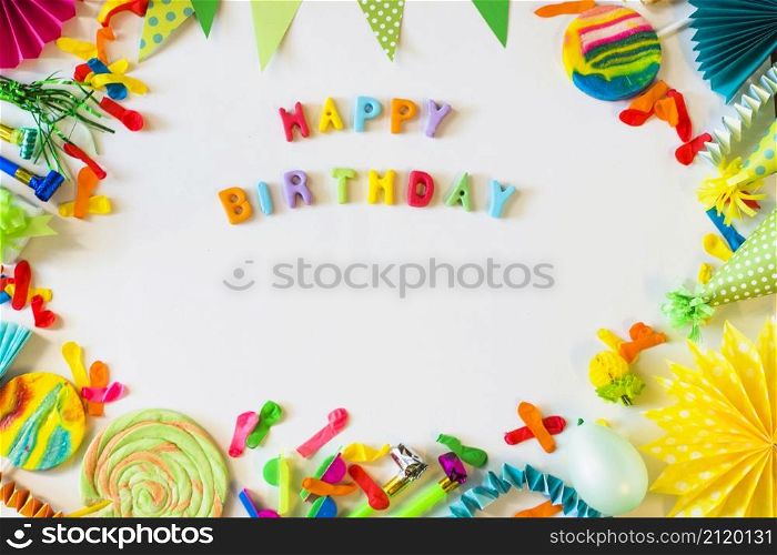 elevated view happy birthday text with party accessories white surface
