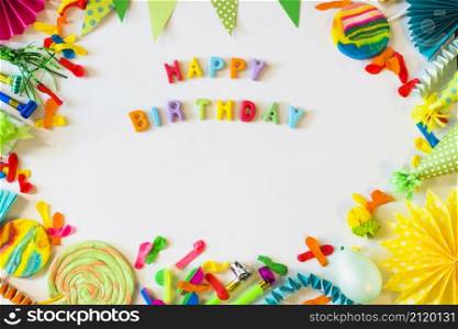 elevated view happy birthday text with party accessories white surface