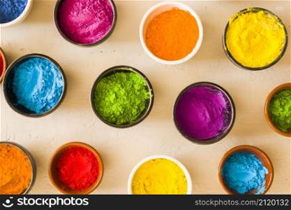 elevated view holi color powder different type bowls concrete backdrop