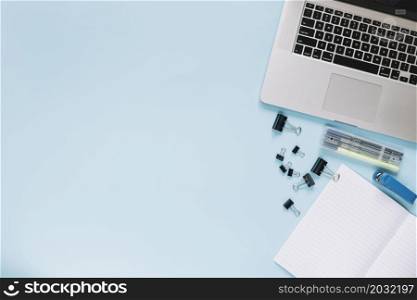 elevated view laptop stationeries blue backdrop