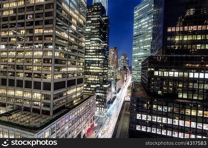 Elevated view of glass fronted skyscrapers illuminated at night, New York, USA
