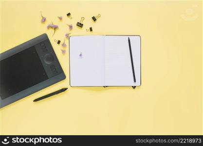 elevated view open notebook graphic digital tablet yellow surface