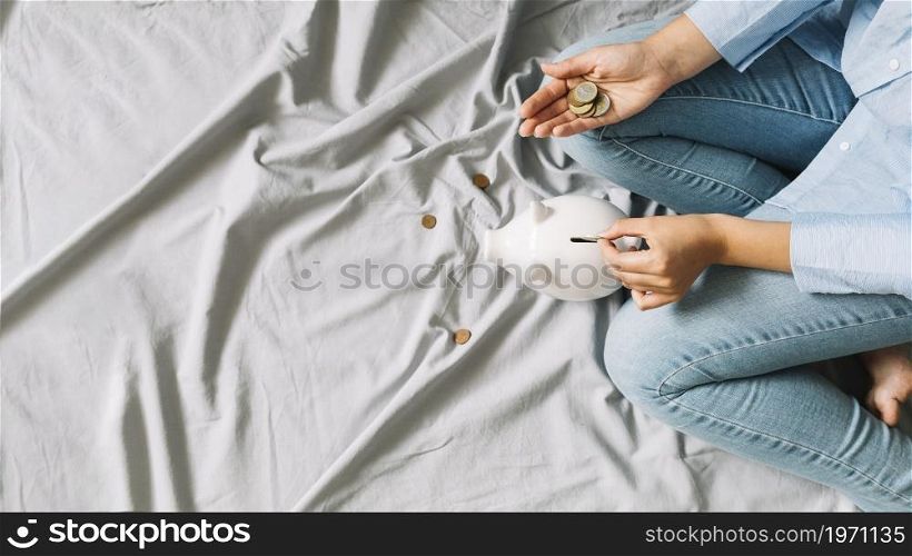 elevated view person s hand inserting coins piggybank. High resolution photo. elevated view person s hand inserting coins piggybank. High quality photo