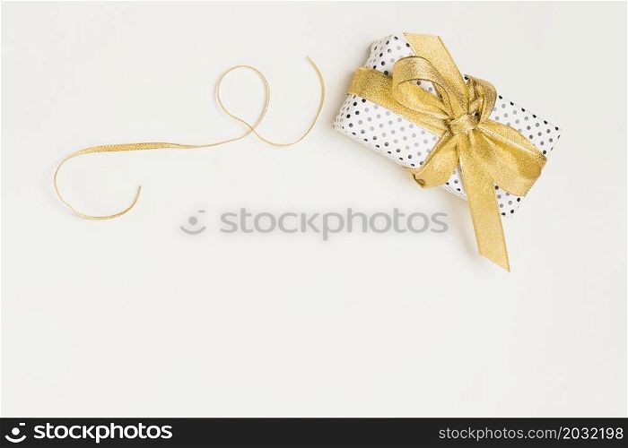 elevated view present box wrapped polka dot design paper with shiny golden ribbon isolated white backdrop