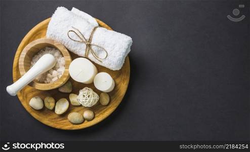 elevated view salt towel candles spa stones wooden plate black backdrop