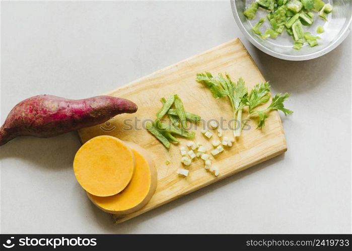 elevated view sweet potato sliced pumpkin celery cutting board