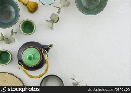 elevated view teapot bowl tea cup brush isolated white backdrop