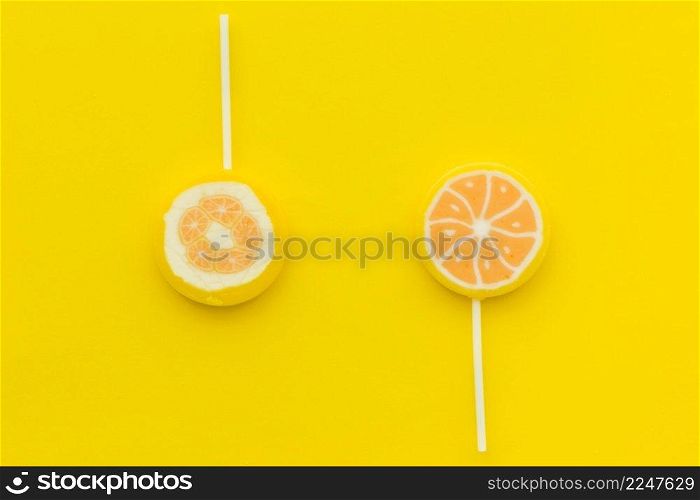 elevated view two sweet citrus lollipops yellow surface