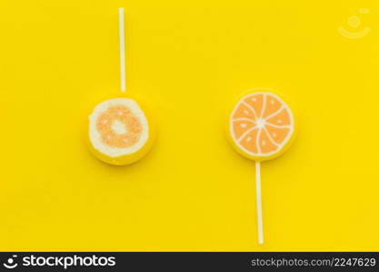 elevated view two sweet citrus lollipops yellow surface