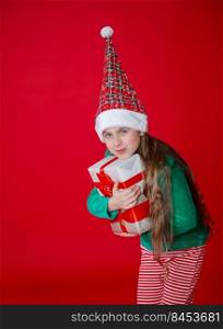 Elf girl with gifts, Santa Claus helper on a bright red bright colored background. Portrait of a beautiful elven baby. Copy space.. Greedy gnome. Elf girl with gifts, Santa Claus helper on a bright red bright colored background. Portrait of a beautiful elven baby.