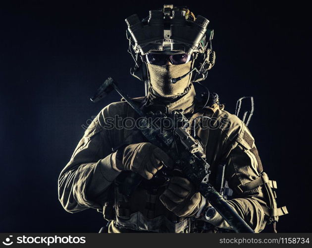 Elite commando fighter, private military company mercenary, special operations serviceman, security or secret service shooter equipped modern weapons and ammunition, studio shoot on black background. Military security service shooter soldier studio portrait