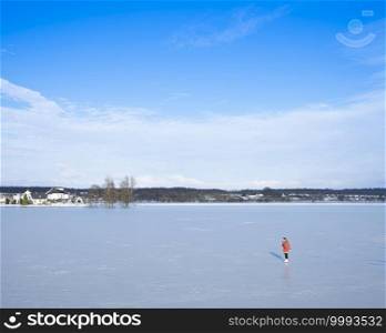 Elst, Netherlands, 10 february 2021  girl in red coat skates on ice of flood planes near river rhine near Rhenen in the centre of the netherlands