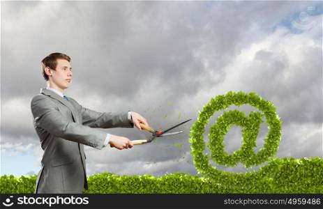 Email concept. Businessman cutting green bush. Network and e-commerce