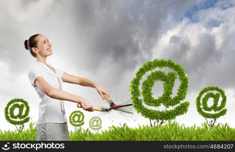 Email concept. Businesswoman cutting green bush. Network and e-commerce