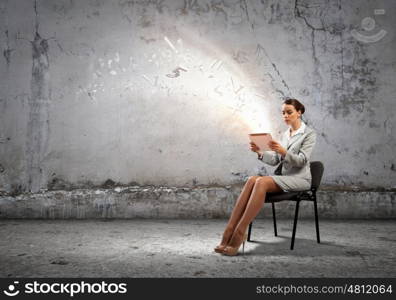 Email concept. Image of businesswoman sitting on chair with tablet pc in hands