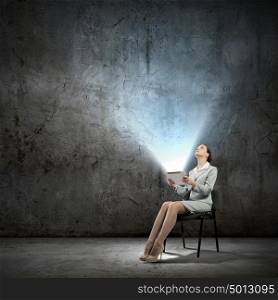 Email concept. Image of businesswoman sitting on chair with tablet pc in hands