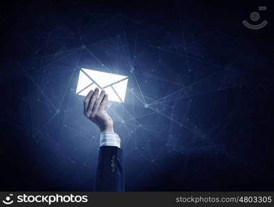 Email concept in hand. Businessman hand on dark background holding email glowing symbols