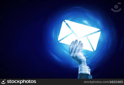 Email concept. Person hand holding glowing email symbol on blue background