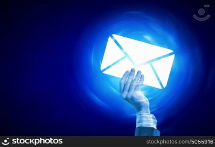 Email concept. Person hand holding glowing email symbol on blue background