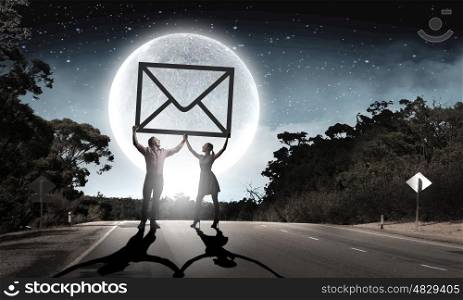 Email concept. Silhouettes of young couple at night holding email sign