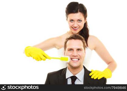 Emancipation idea concept. Humorous funny wedding couple bride and groom. Woman brushing teeth of her man showing her domination and taking control. Isolated on white.