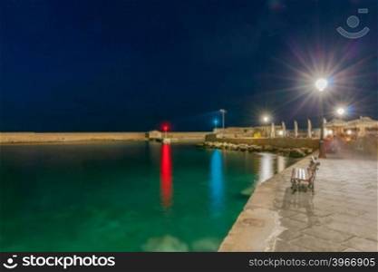 Embankment and the harbor entrance with navigation lights at night in Chania.. Chania. The old harbor at night.