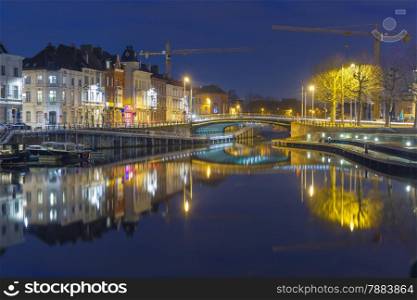 Embankment of the river Leie, bridge and reflections colored houses in Ghent town at night, Belgium