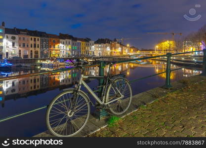 Embankment of the river Leie with bike and reflections colored houses in Ghent town at night, Belgium