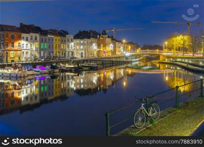 Embankment of the river Leie with bike and reflections colored houses in Ghent town at night, Belgium