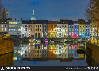 Embankment of the river Leie with reflections colored houses and Belfry tower in Ghent town at night, Belgium