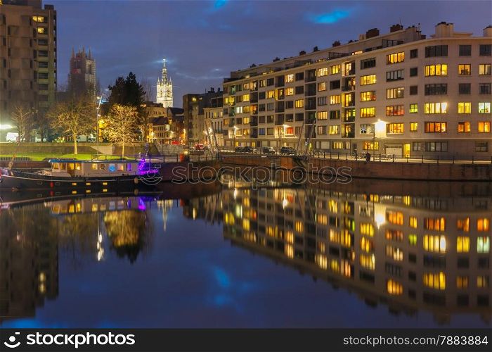 Embankment of the river Leie with reflections colored houses and Belfry tower in Ghent town at night, Belgium