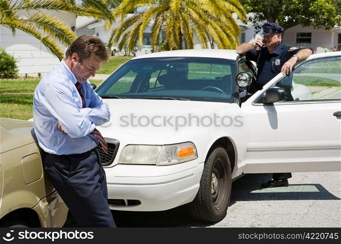 Embarassed looking businessman pulled over by the police. Focus is on the businessman.