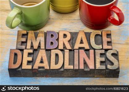 embrace deadlines - word abstract in vintage letterpress wood type blocks with cups of coffee