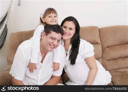 Embracing a happy family with child at home and expectant mother