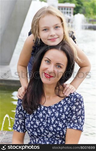 Embracing brunette mother and blond daughter with long hairs