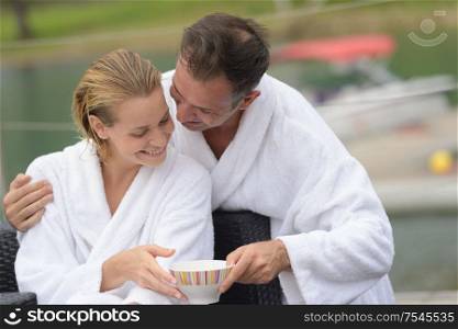Embracing couple in bath robes holding bowl