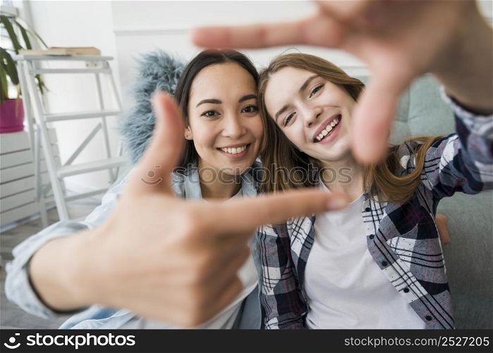 embracing girls smiling making frame with hands like selfie