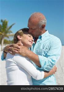 Embracing senior couple kissing on tropical beach