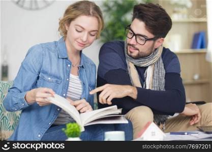 embracing young couple reading book on sofa