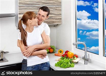 Embracing young enamoured couple at kitchen