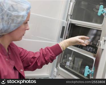 Embryologist putting sample into incubator (selective focus)