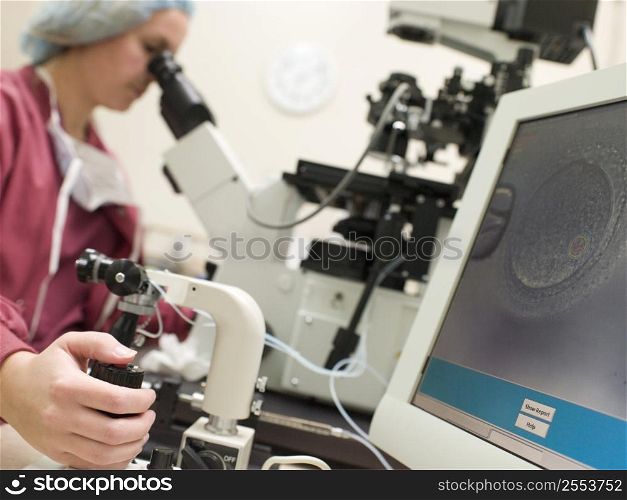 Embryologist with microscope performing an intra cytoplasmic sperm injection (selective focus)
