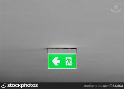 Emergency exit sign with left arrow in department store. Safety first concept. Copy space wallpaper.