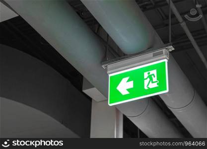 Emergency exit sign with left arrow in department store. Safety first concept. Copy space wallpaper.