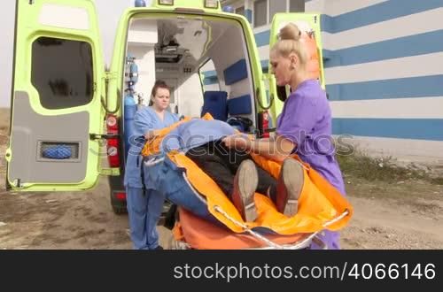 Emergency medical service team of paramedics fixing senior female patient on the ambulance stretcher