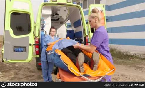 Emergency medical service team of paramedics fixing senior female patient on the ambulance stretcher