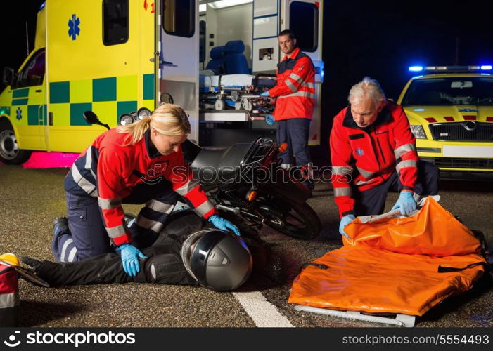 Emergency team assisting injured motorbike man driver at night