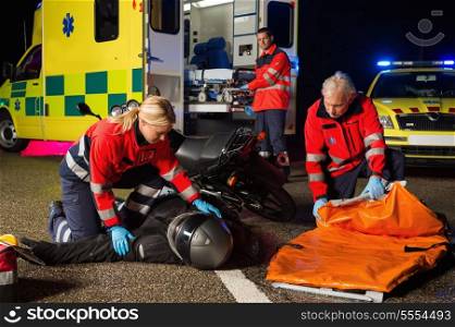 Emergency team assisting injured motorbike man driver at night